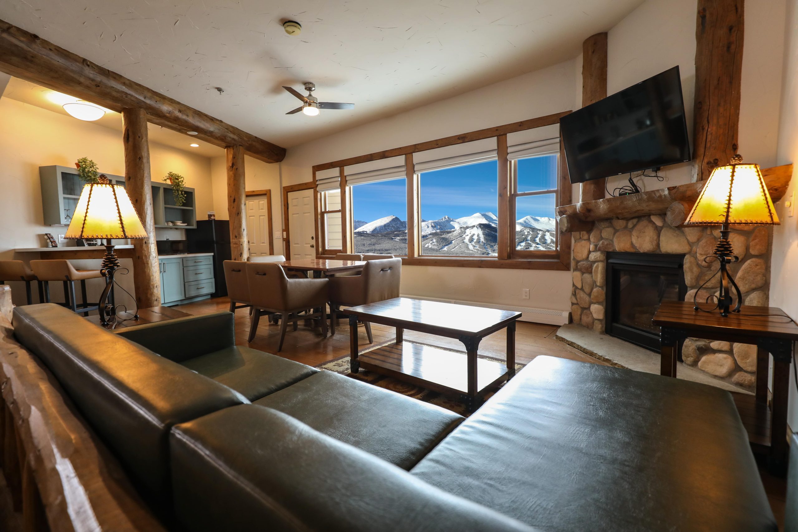 Cozy suite with leather sofa, stone fireplace, and big mountain window.