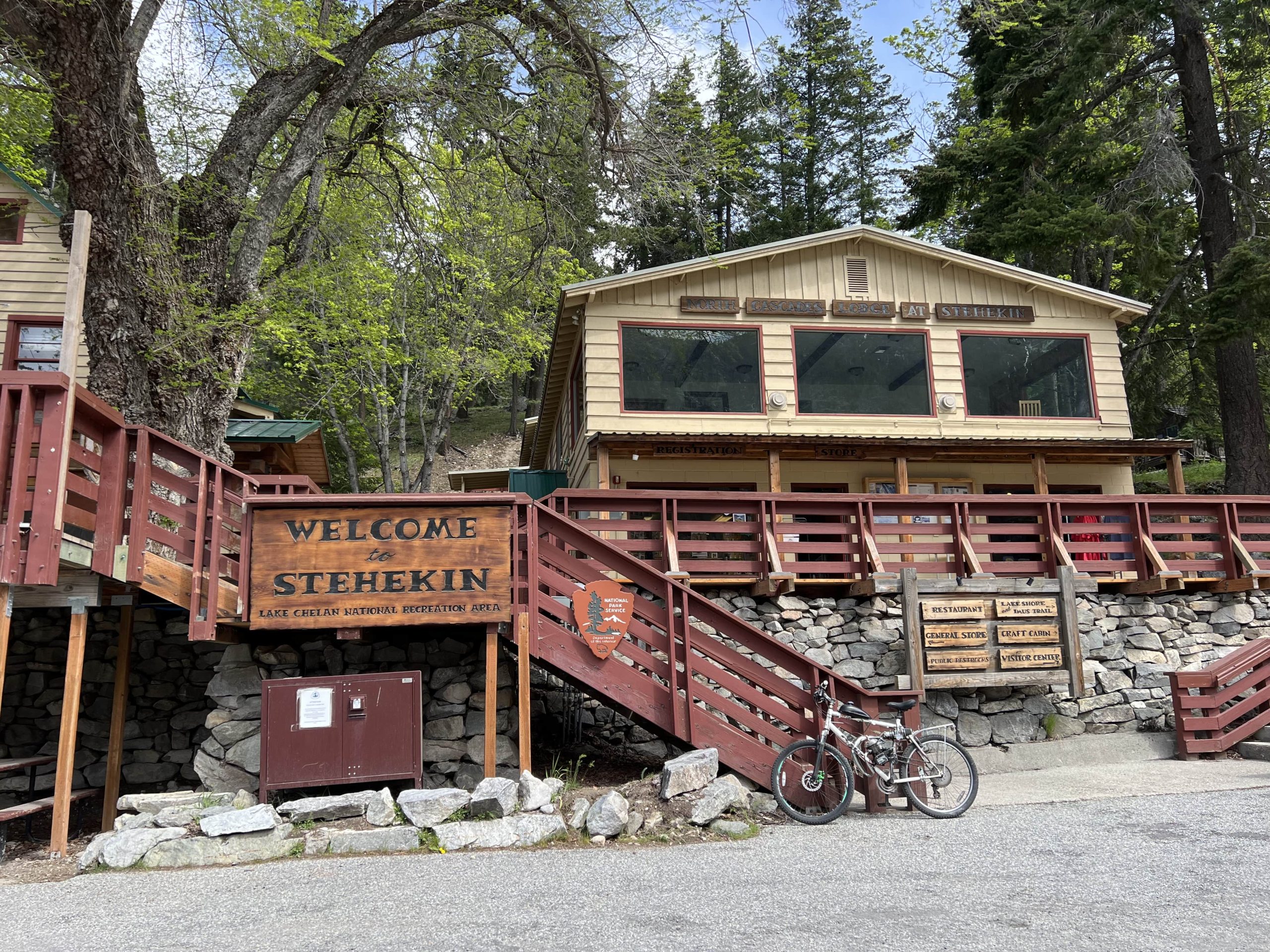 Entrance to rustic North Cascades lodging at Stehekin, Lake Chelan, with welcome sign, lodge, and nearby visitor amenities.