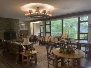 Cosy lounge area at Bear Mountain Inn with rustic wooden furniture, stone fireplace, and scenic views through large windows.
