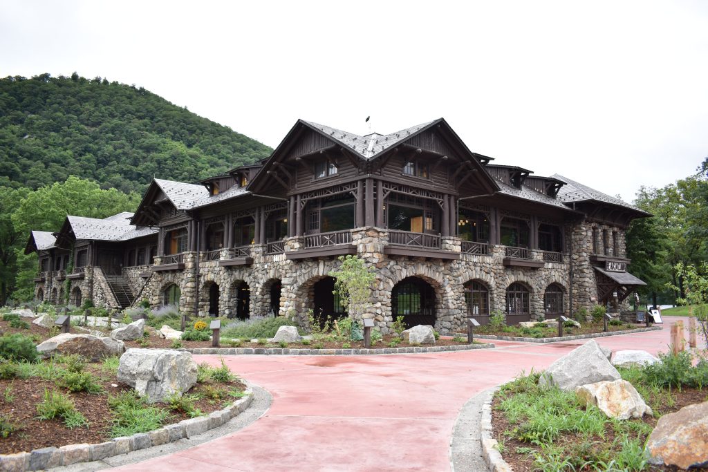 Historic stone building at Bear Mountain State Park, surrounded by gardens, rock formations, and green mountains.
