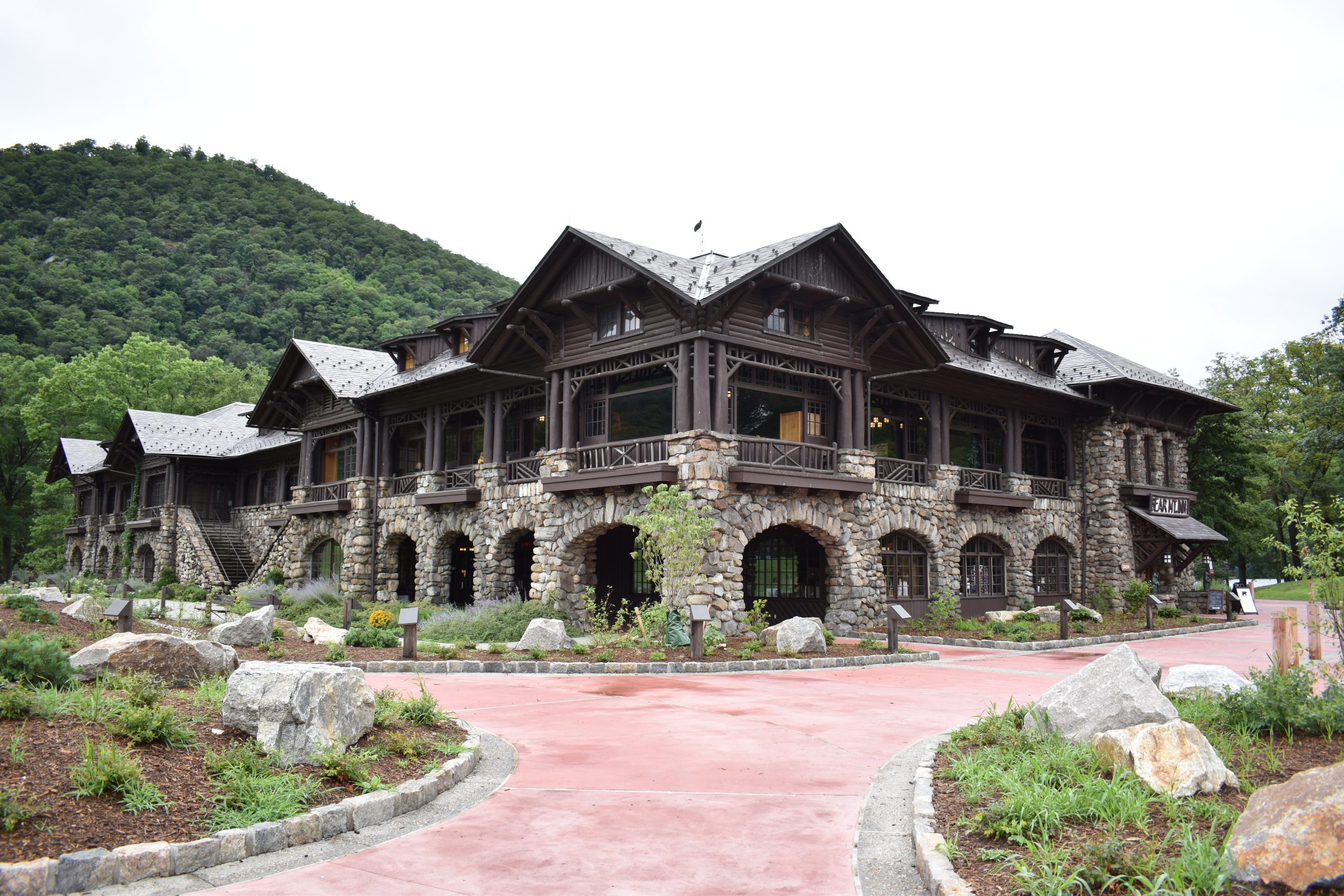 Historic stone building at Bear Mountain State Park, surrounded by gardens, rock formations, and green mountains.